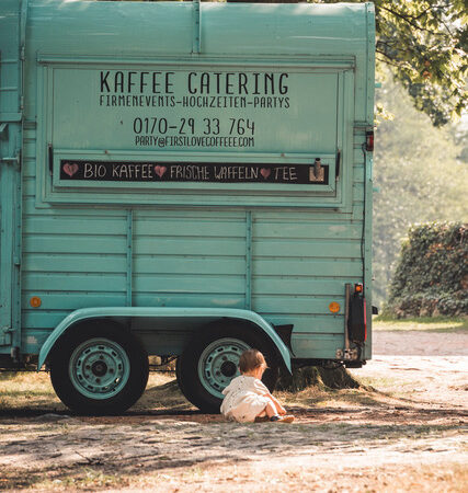 Kleines Kind sitzt vor dem FirstLoveCoffee Anhänger
