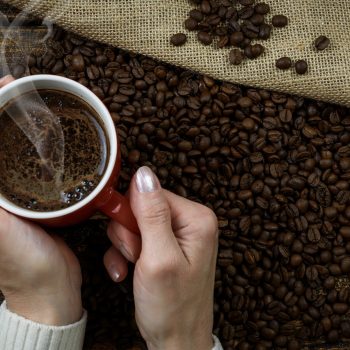 Dampfend heißer Kaffee in Mitten von Kaffee-Bohnen